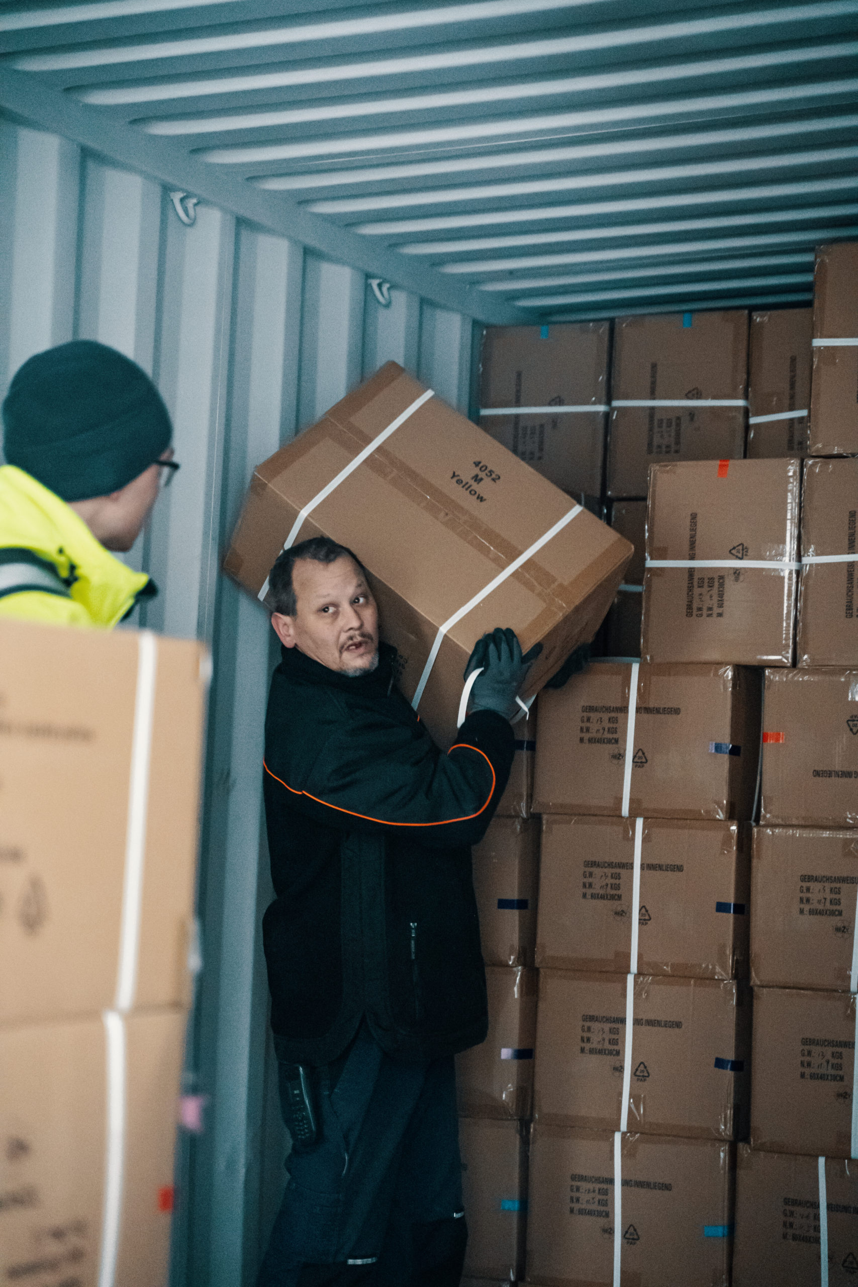 Mitarbeiter im lager heben einen Karton au einem LKW